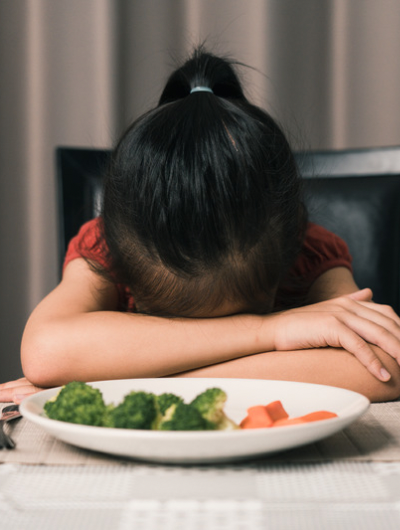 Girl with head on the table refusing food